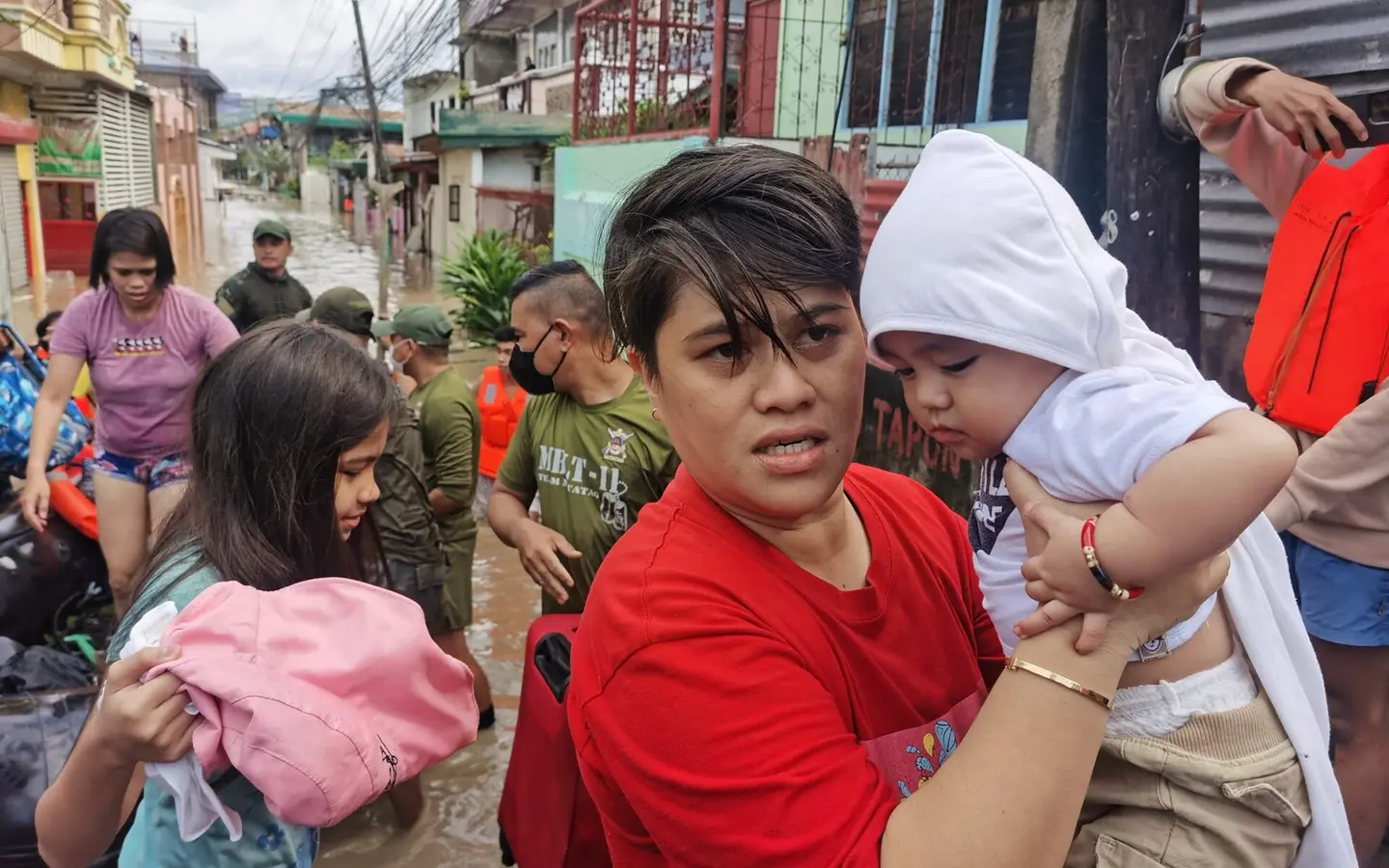A woman carrying a baby during a storm rescue operation in the Philippines
