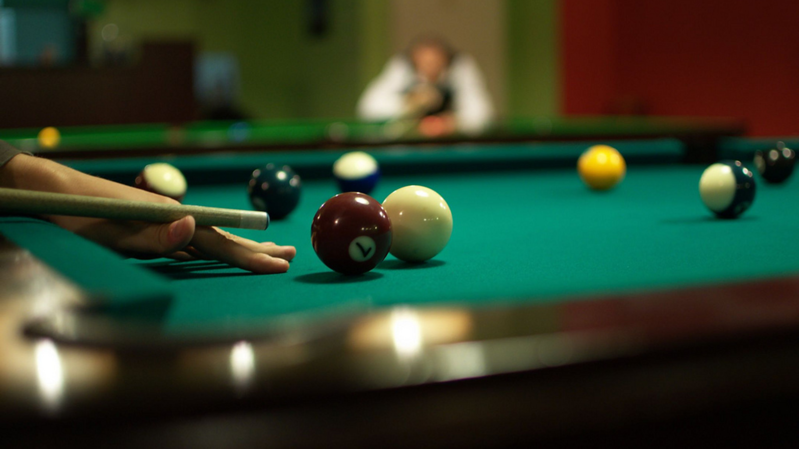 Billiards player lining up a shot on a pool table
