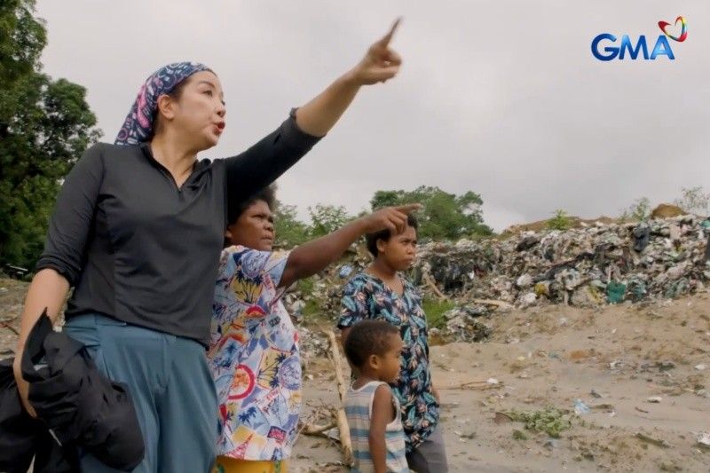 Journalist Kara David and Aeta community members looking across accumulated waste at the Subic site